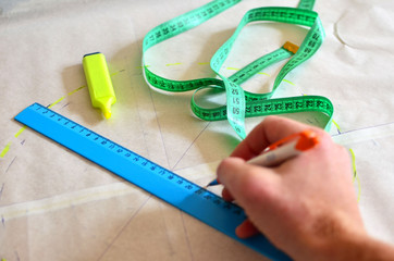 Woman designer making sketch out patterns that need to be transferred to the fabric to obtain...