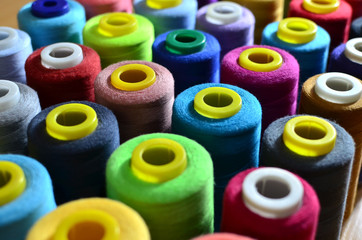 Background of bobbins with multicolored threads for sewing. Needlework, sewing and tailoring concept. Fabric and textile industry