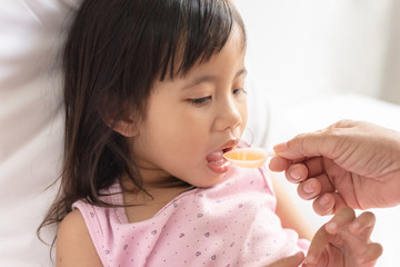 Unhappy asain girl when taking medicine syrup from her mother