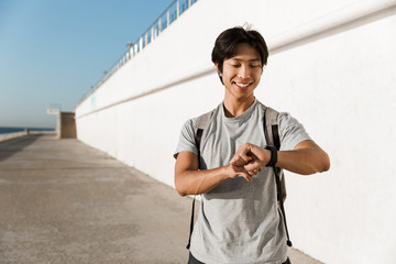 Smiling young asian man wearing backpack