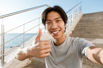 Cheerful asian man taking a selfie while standing on a staircase