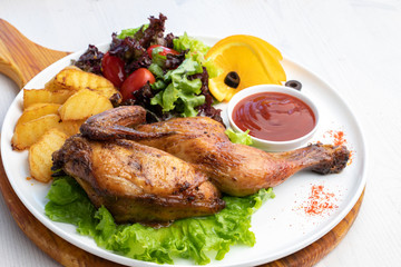 Fried chicken with potatoes and fresh salad on a white plate