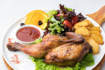 Fried chicken with potatoes and fresh salad on a white plate