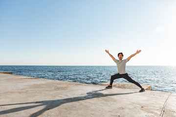 Calm healthy asian man doing yoga exercises at the beach