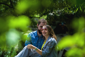 The young and modern loving couple sits among greens in the park. positive emotions. Happiness. Family.