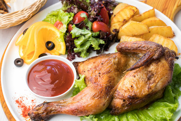 Fried chicken with potatoes and fresh salad on a white plate