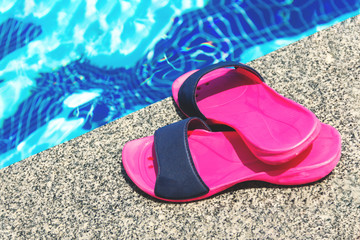 Summer background with slippers for the pool fuchsia colors near the pool