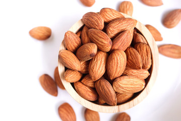 Almond nuts in wooden bowl on white background.