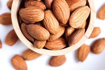 Almond nuts in wooden bowl on white background.