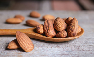 Almond nuts in wooden spoon on rustic background.