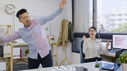 Concept of team spirit achievement concept. young woman colleague looking at handsome man manager dancing in office. two creative partner male and female cheerful win celebrating in modern studio.