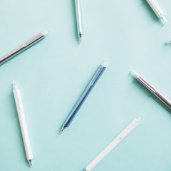 Elevated view of various pens on turquoise colored background
