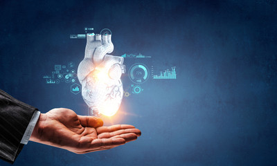 Man`s hands showing anatomical heart model. Mixed media.