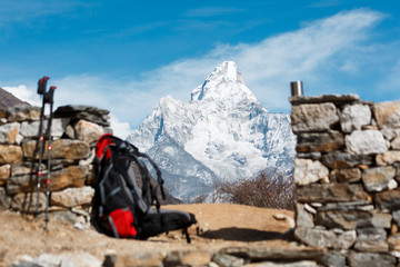 Everest trekking. Mountain Ama Dablam in focus. Backpack, mug and poles in the foreground blurred