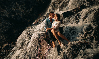 Couple hugging under the streams of a waterfall.