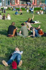 Girl on the green grass. People at an open-air concert