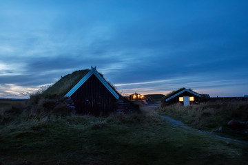 Fototapeta na wymiar Houses with a grass-covered roof at dusk on the meadow in the evening. Iceland.