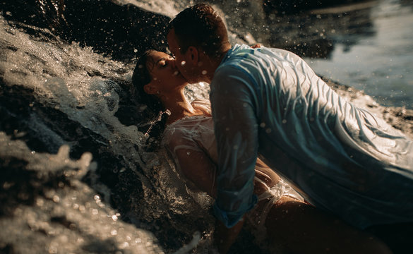 A couple during lovemaking next to a waterfall.