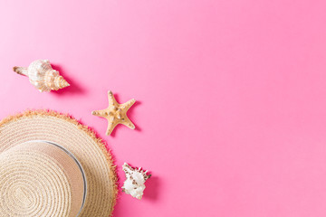 Beach hat with seashells on pink wooden table. summer background concept with copy space top view