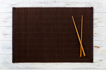 two sushi chopsticks with empty bamboo mat or wood plate on white wooden Background Top view with...