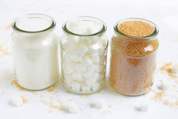 Various types of sugar in a glass jar on white