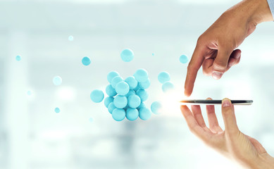 Businessman hands holding a smartphone with a bunch of spheres levitating above. Mixed media