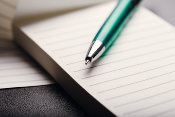 Opened notepad with automatic plastic ballpoint pen close up. Toned vintage