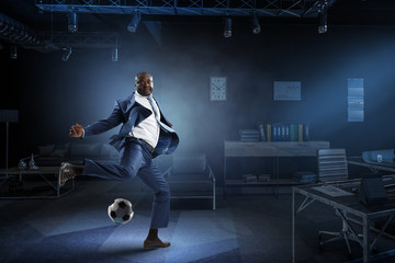 Black businessman in a suit plays football