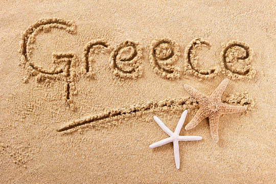 Greece word written in sand sign writing drawing drawn on a sunny summer beach with starfish holiday vacation travel destination message photo