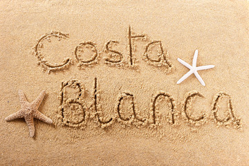 Fototapeta na wymiar Costa Blanca spain word written in sand sign writing drawing drawn on a sunny spanish summer beach with starfish holiday vacation travel destination message photo