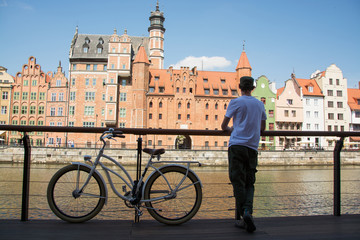 Obraz premium Young couple of travelers with retro bicycle stand near river in old gdansk city 