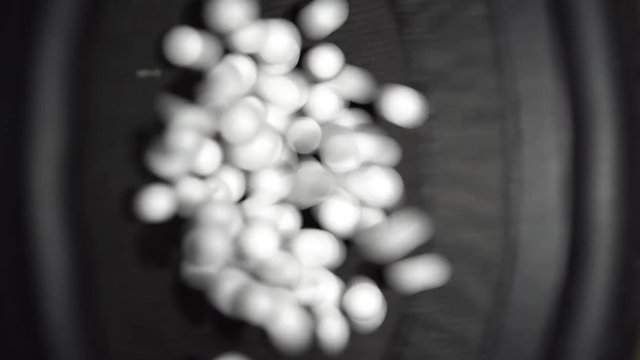 Close-up vertical view of white polystyrene beads jumping on a working speaker surface by acoustic waves