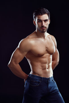 Portrait of an athletic man with a naked torso on a black background.