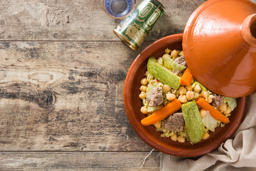 Traditional tajine with vegetables, chickpeas, meat and couscous on wooden table. Top view....