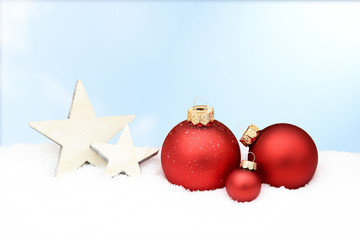 red christmas baubles and wooden star lying in snow