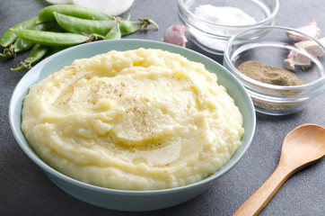 Delicious mashed potatoes in the bowl,peas, spices,garlic on the grey table