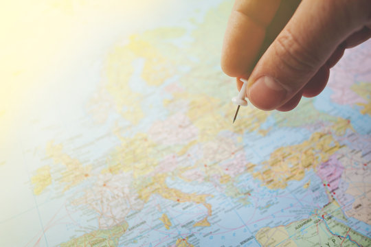 pushpin in hand over a blurred world map