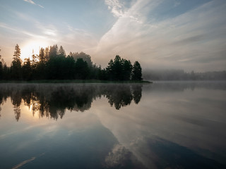 Foggy and mystical lake landscape before sunrise. All silhouettes are blurry and unclear. Vaidavas lake, Latvia