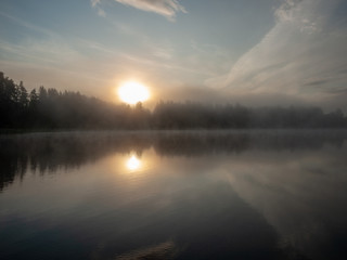 Obraz premium Foggy and mystical lake landscape before sunrise. All silhouettes are blurry and unclear. Vaidavas lake, Latvia