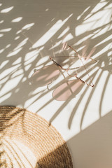 Fashion composition with women's accessories on white background with leaves shadow. Sunglasses,...