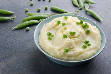 Delicious hot mashed potatoes with peas on the grey table