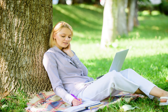 Natural environment office. Work outdoors benefits. Woman with laptop computer work outdoors lean on tree trunk. Girl work with laptop in park sit on grass. Education technology and internet concept