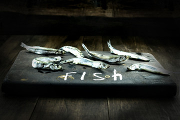 Seafood. Small sea fish, anchovies, capelin, smelt, on dark background Fish pattern