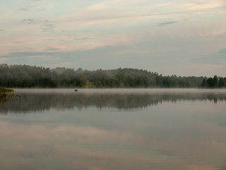 Foggy and mystical lake landscape before sunrise. All silhouettes are blurry and unclear. Vaidavas lake, Latvia