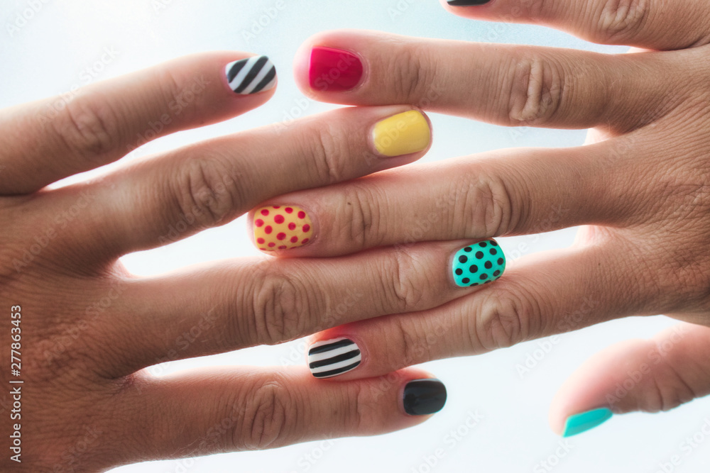 Wall mural a pair of female hands with colored painted nails with different patterns