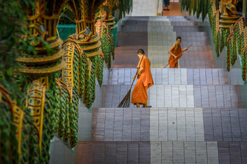Buddhistische Mönche in einem thailändischen Tempel reinigen die Treppe