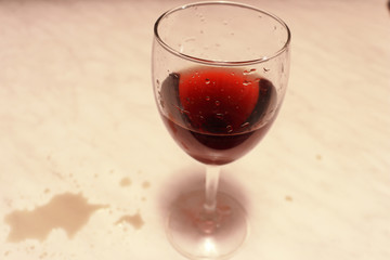  A glass of red wine on the marble table. Wine drops on the marble table.