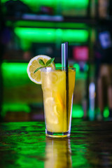 Orange cocktail in a tall glass and a slice of lemon.