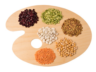 Collection of legumes on wooden art palette, isolated on white background.