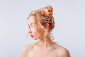 Young blonde girl with an original hairstyle and bright professional makeup